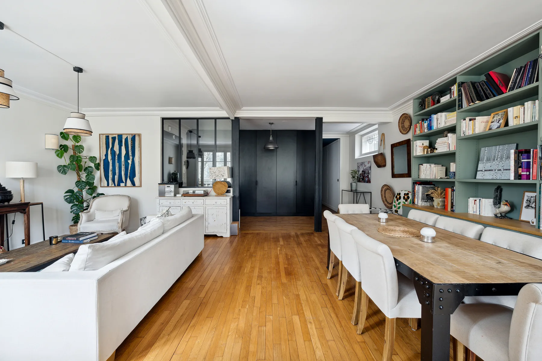 Una luminosa sala de estar y comedor con asientos blancos y una larga mesa de madera.