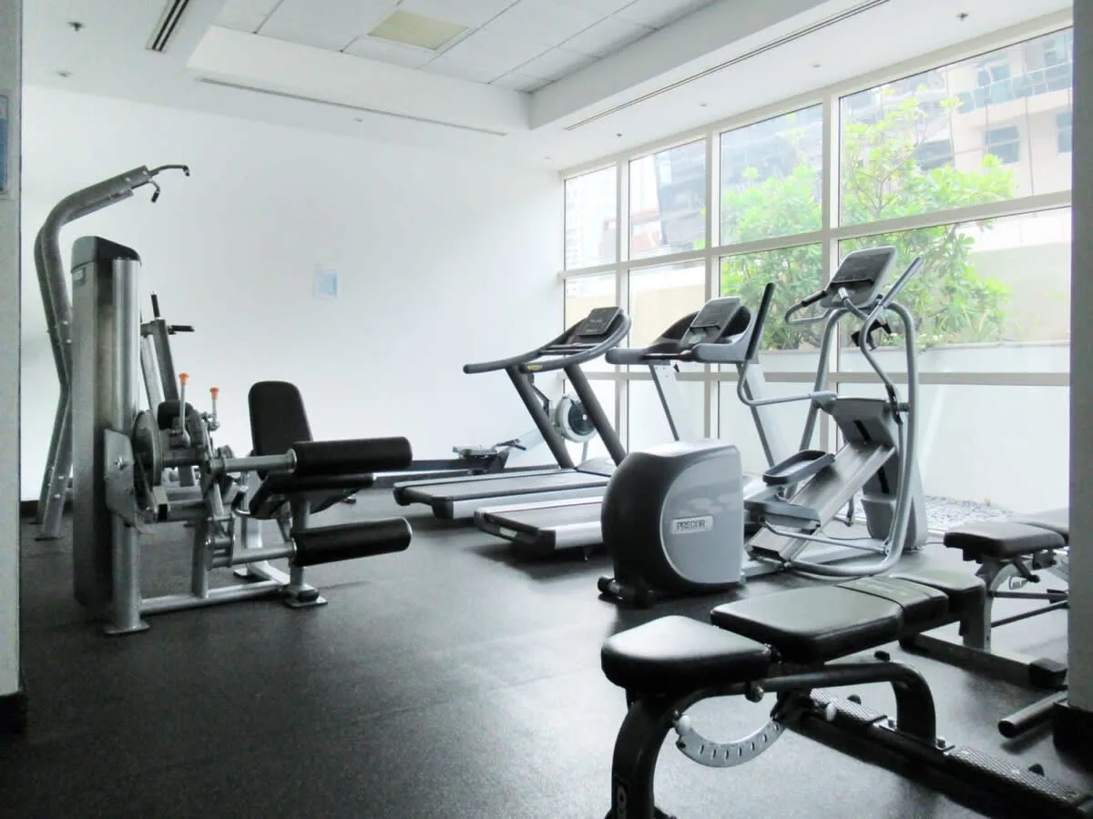 A gym with exercise machines and large windows.
