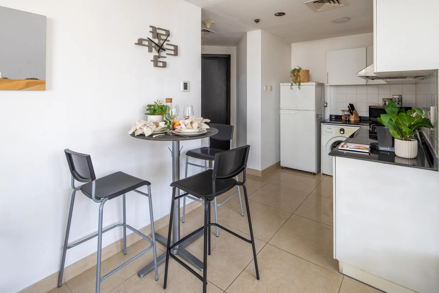 A compact dining area opens onto a kitchen, with a table and seating.