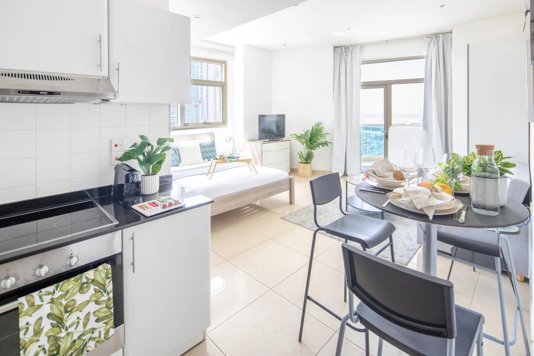 A bright open-plan kitchen and dining area with seating beside large windows.
