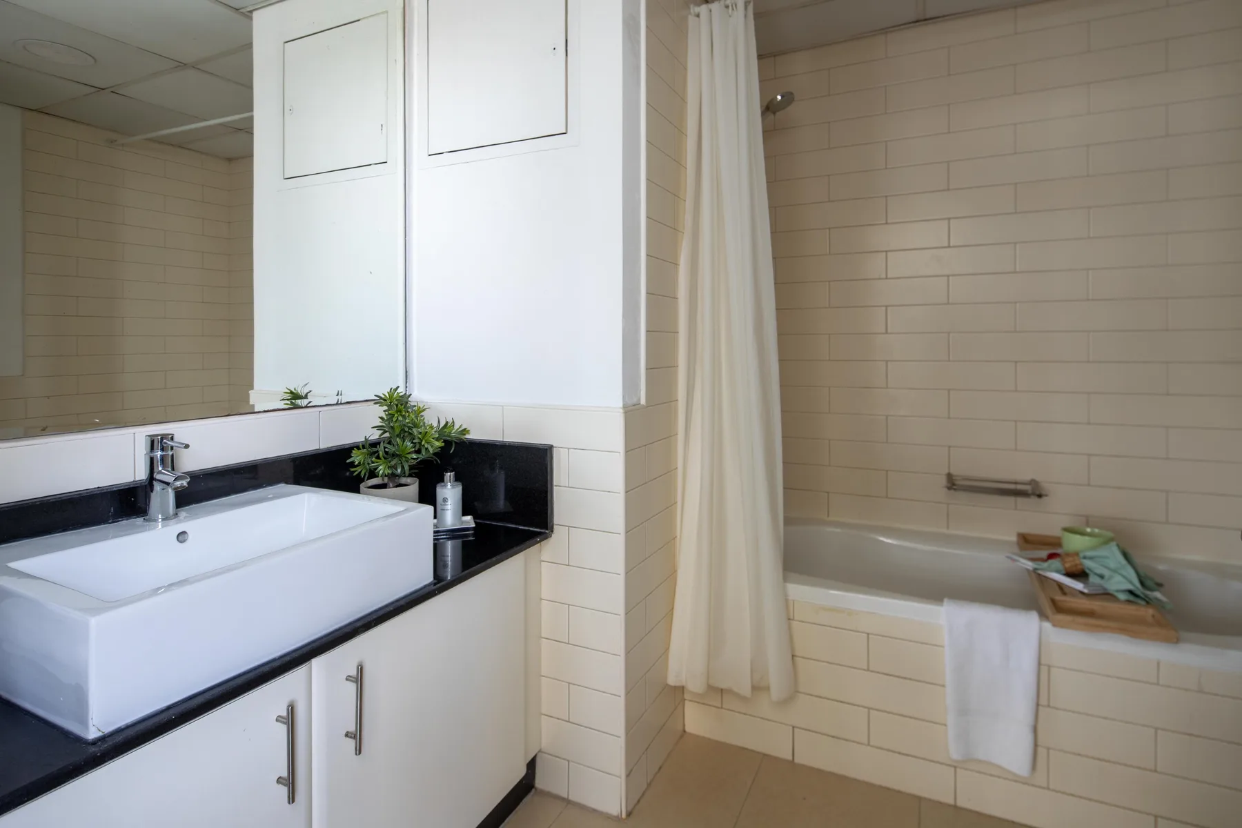 A bathroom with a sink beside a bathtub and shower curtain.