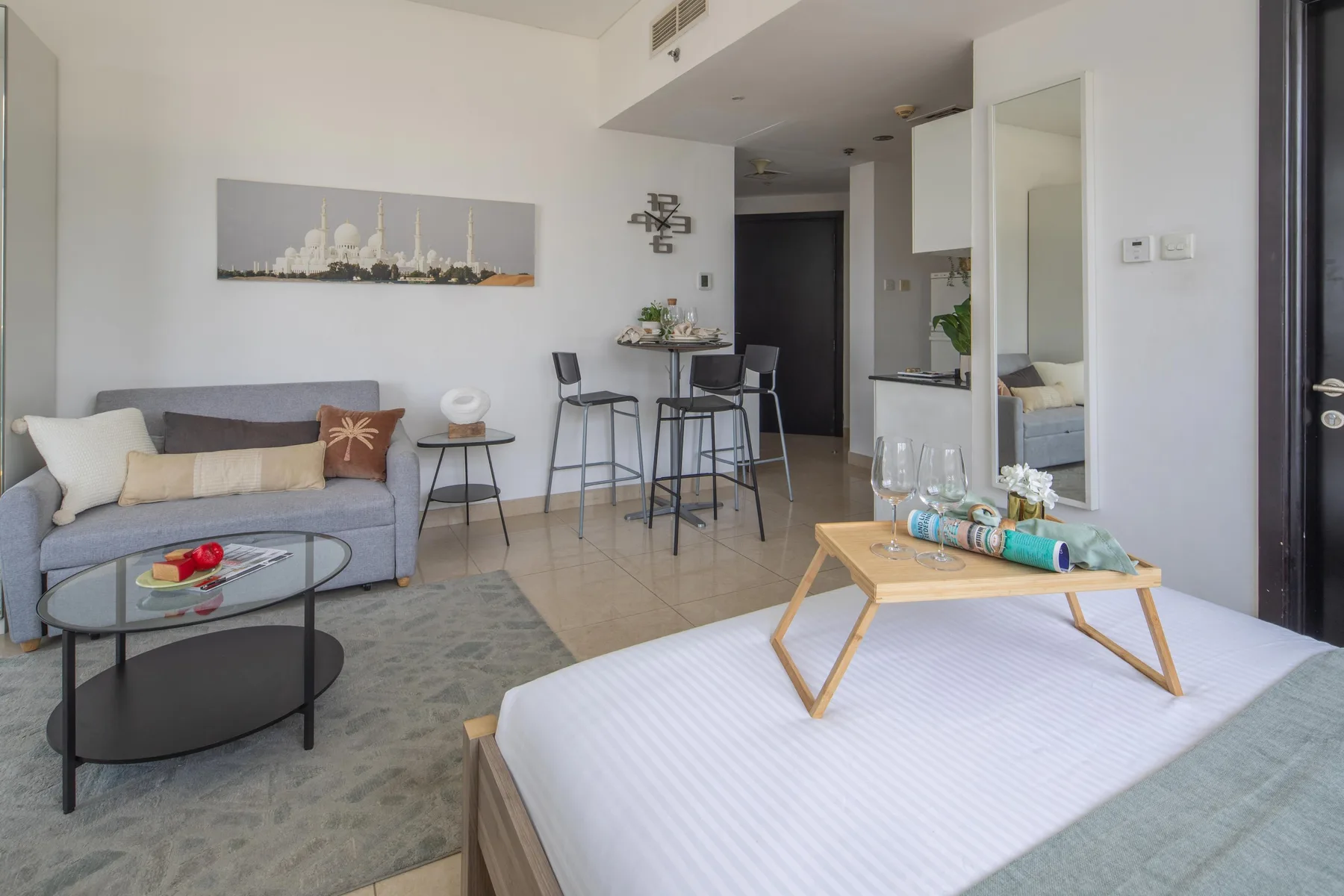 A bright living area with a bed, seating, and a small dining counter.