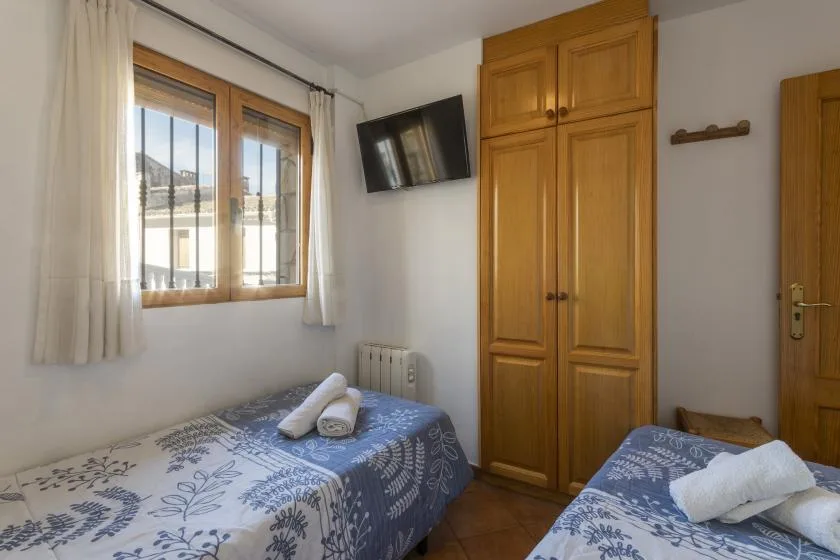 Un dormitorio con camas individuales, ropa de cama estampada, una ventana y un armario de madera.