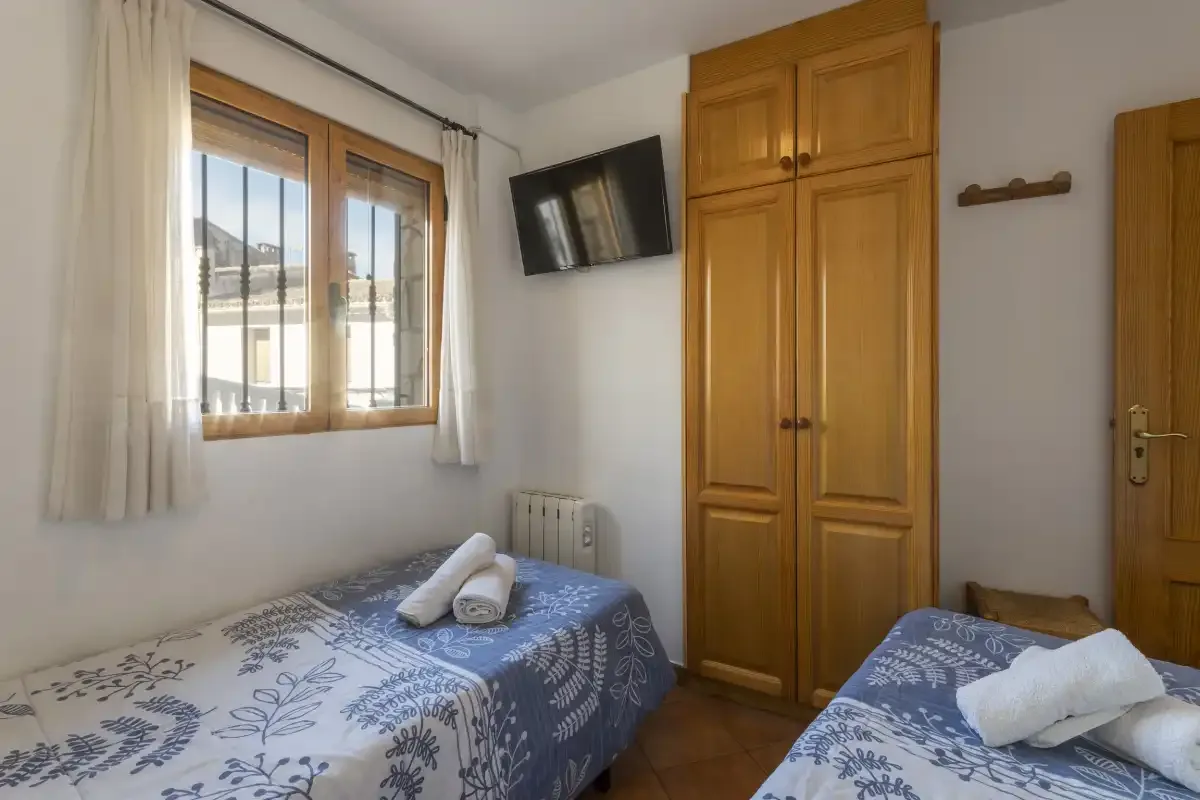 Un dormitorio con dos camas, una ventana y un armario de madera.