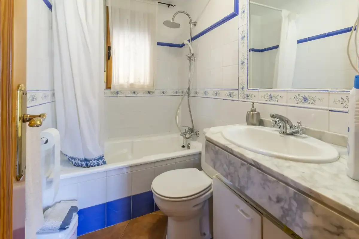 Un baño con bañera, inodoro y lavabo bajo un espejo grande.
