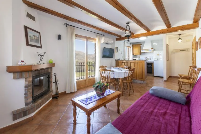 A living and dining area opens onto a compact kitchen, with a fireplace and glass doors.