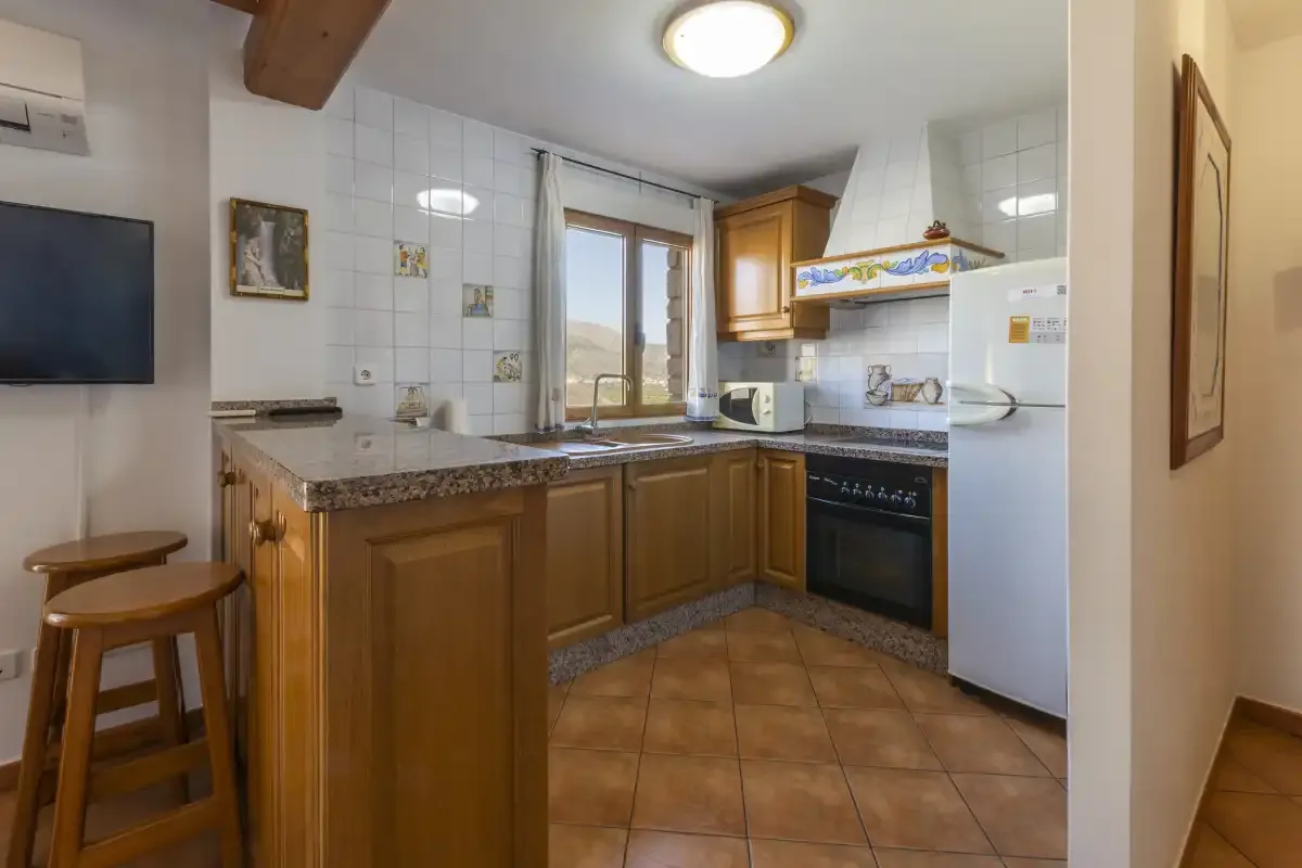 Una cocina alicatada con armarios de madera, una encimera central y una ventana.