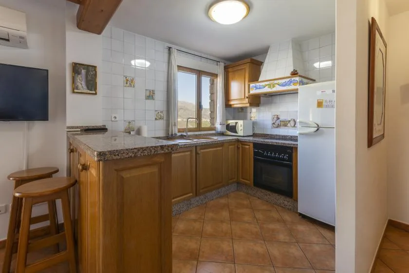 Una cocina alicatada con armarios de madera, una encimera y una ventana sobre el fregadero.
