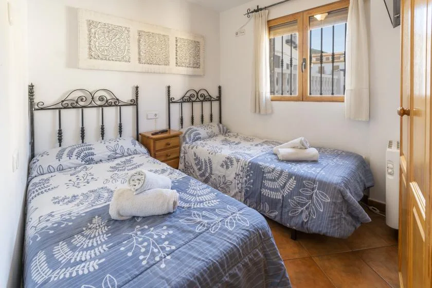 Un dormitorio con camas individuales, ropa de cama estampada y una ventana con edificios a la vista.