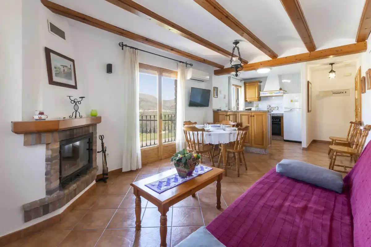 Una sala de estar y comedor se abre a la cocina, con una chimenea y puertas al balcón.