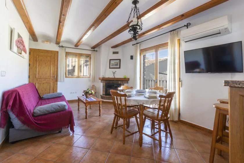 Una zona de estar y comedor con mesa de madera, asientos y chimenea.