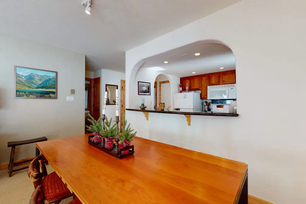 A dining area with a wooden table facing an open kitchen.
