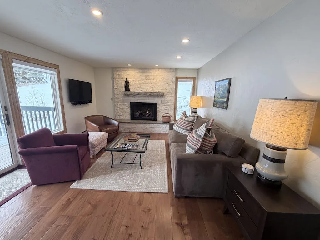 A living room with seating arranged around a coffee table and fireplace.