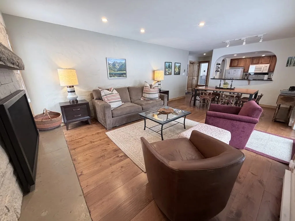 A living room with seating, a coffee table, and an open dining area.
