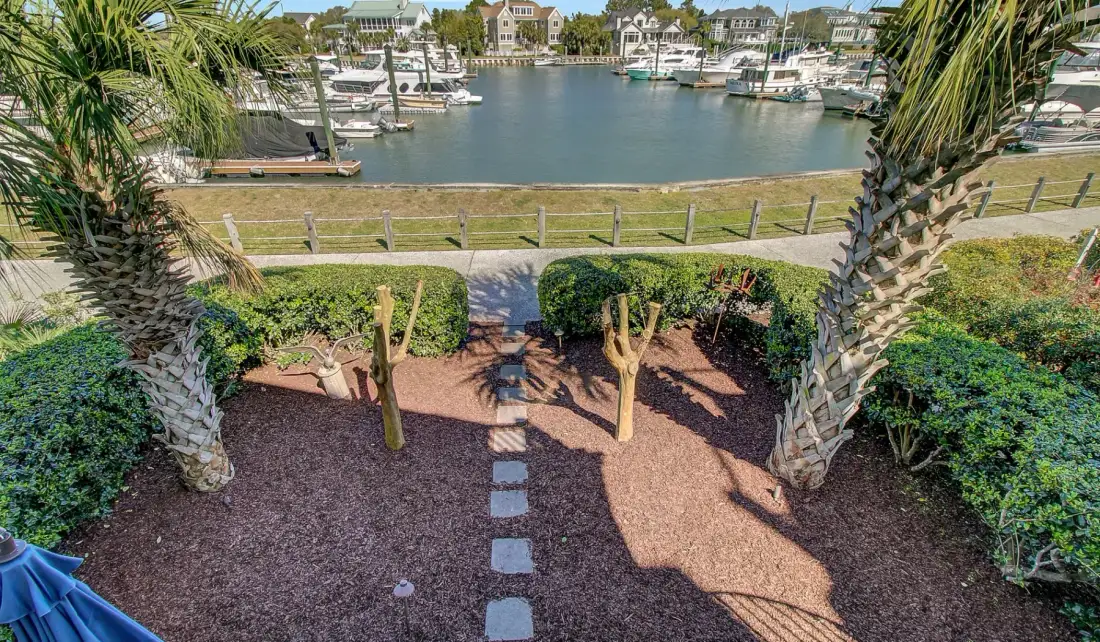 Un jardín ajardinado con piedras para pisar da a una marina.
