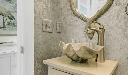 Un tocador de baño con un lavabo decorativo y un grifo alto.