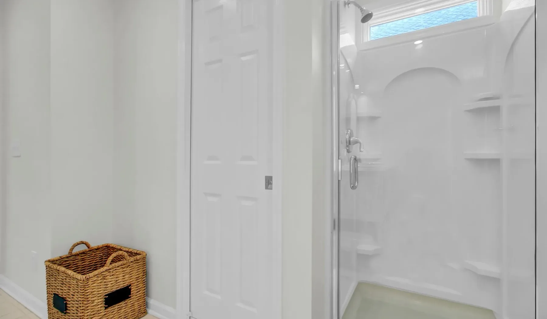 Un baño con ducha, estantes empotrados y una cesta tejida.
