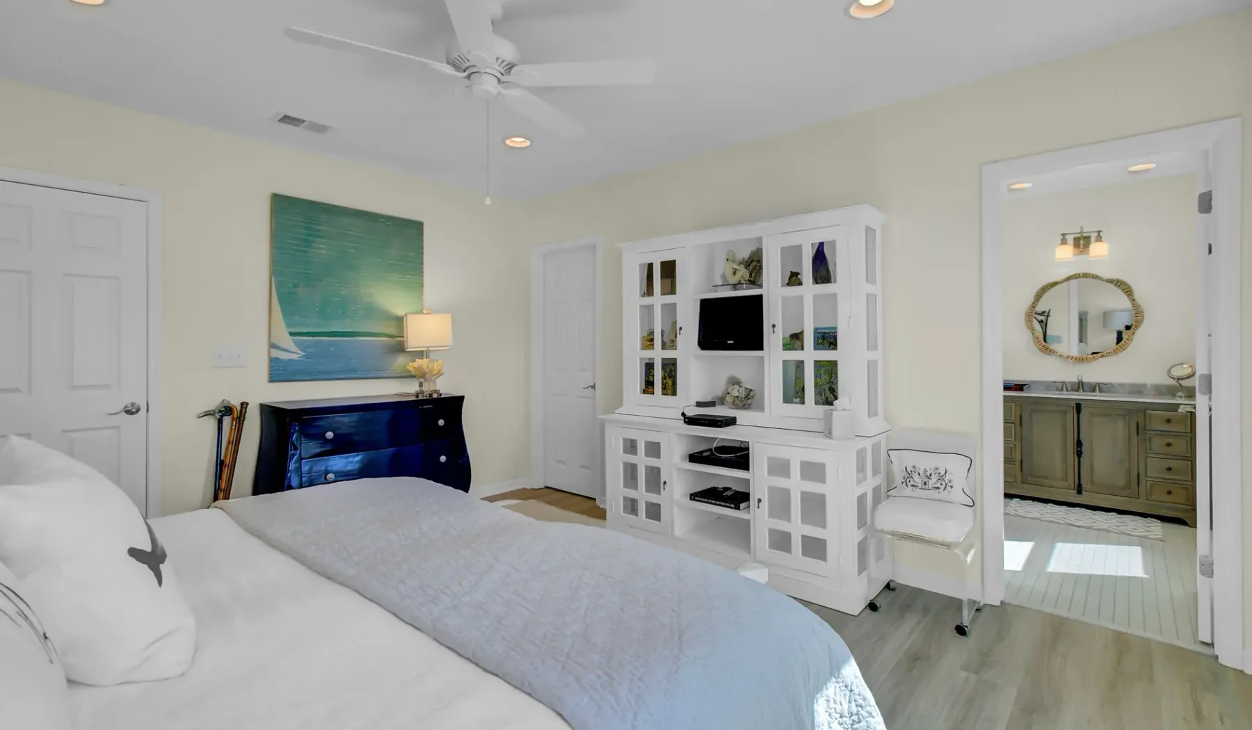 Un dormitorio con una cama, un mueble blanco y una puerta abierta hacia un baño.
