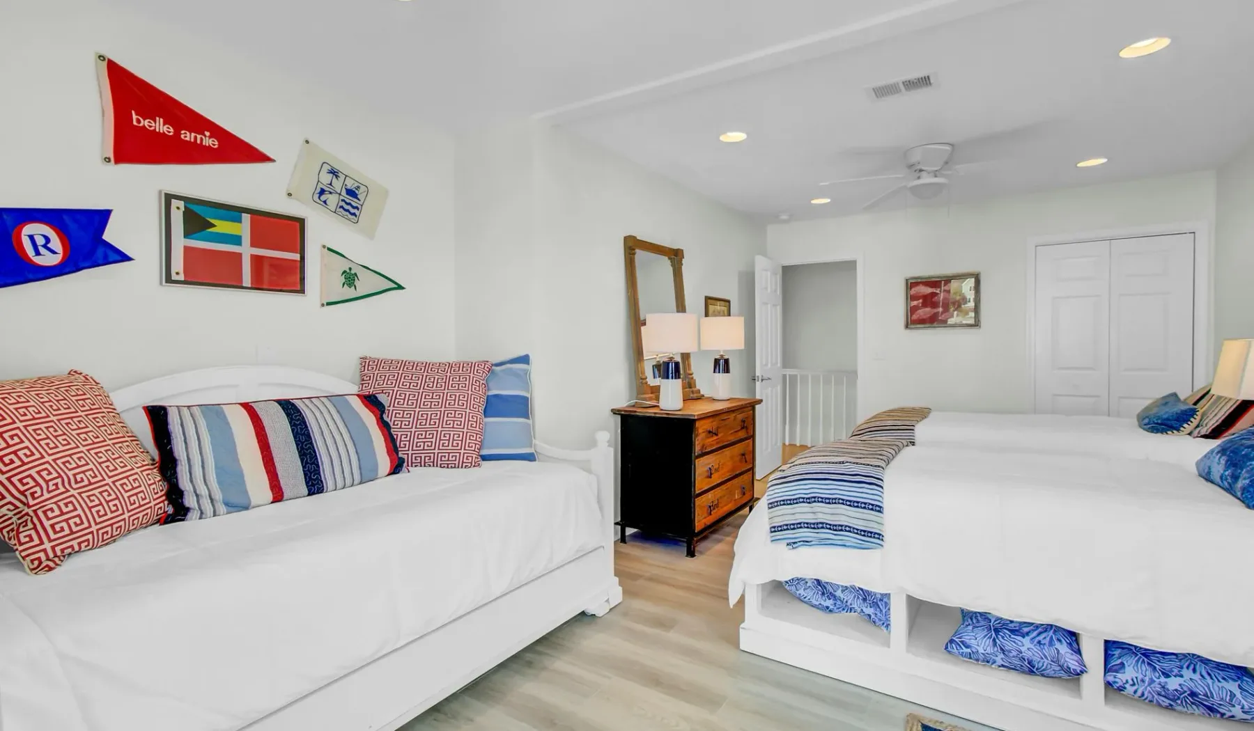 Un dormitorio luminoso con dos camas, almohadas coloridas y una cómoda de madera.