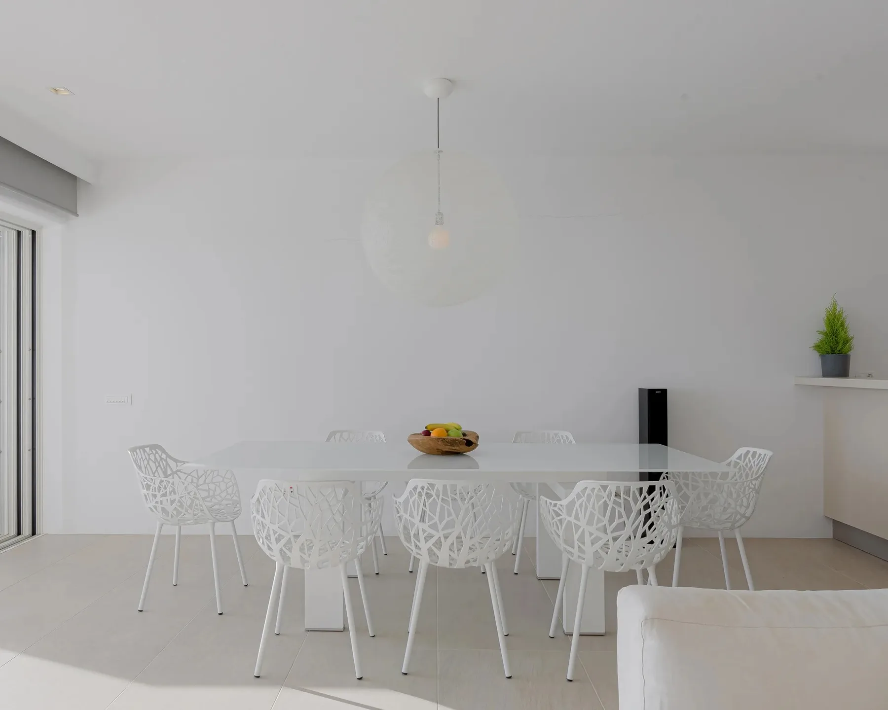 A bright dining area has a white table and patterned seating.