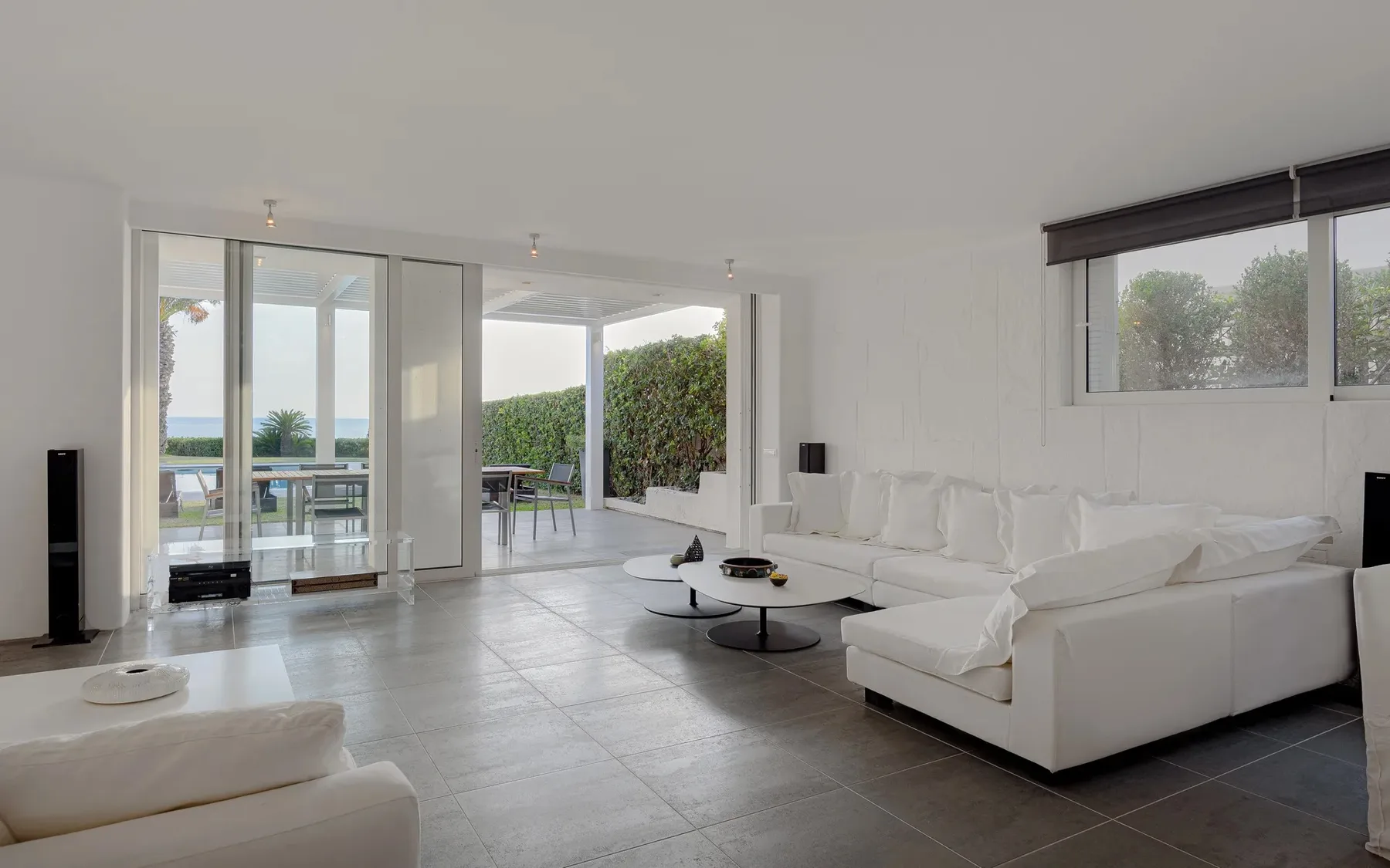 A bright living room with white seating and glass doors opening onto a patio.