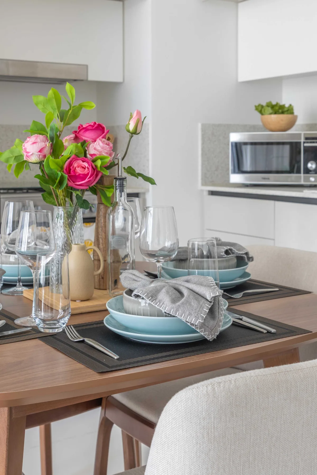 A dining table is set with dishes and flowers in a bright kitchen.