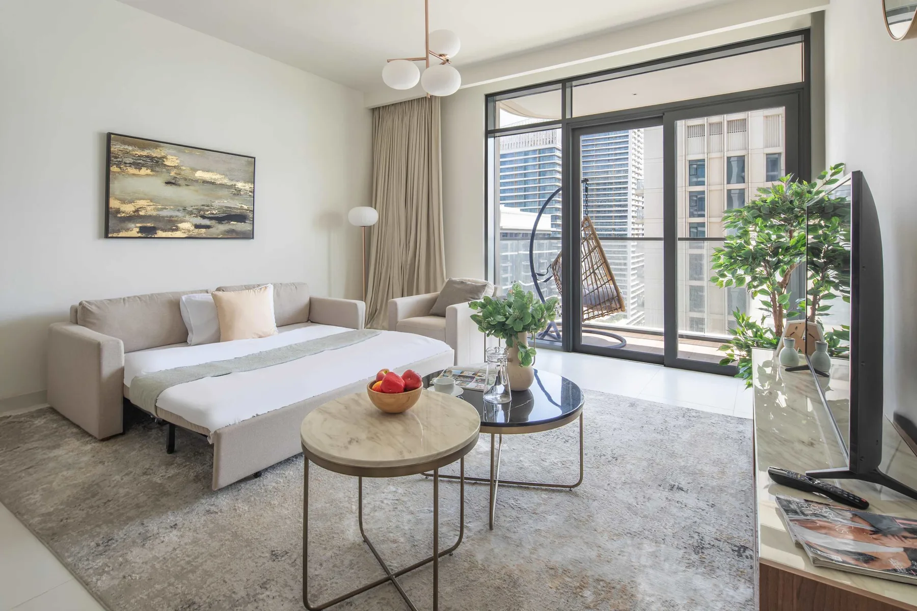 A bright living room with a sofa bed and large windows opening onto a balcony.
