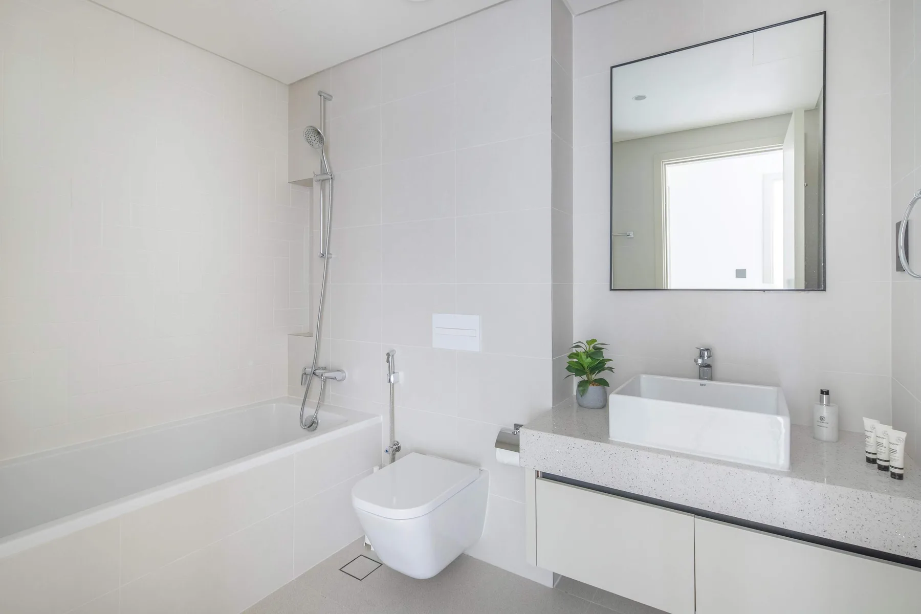 A bright bathroom with a bathtub, shower, toilet, and sink.