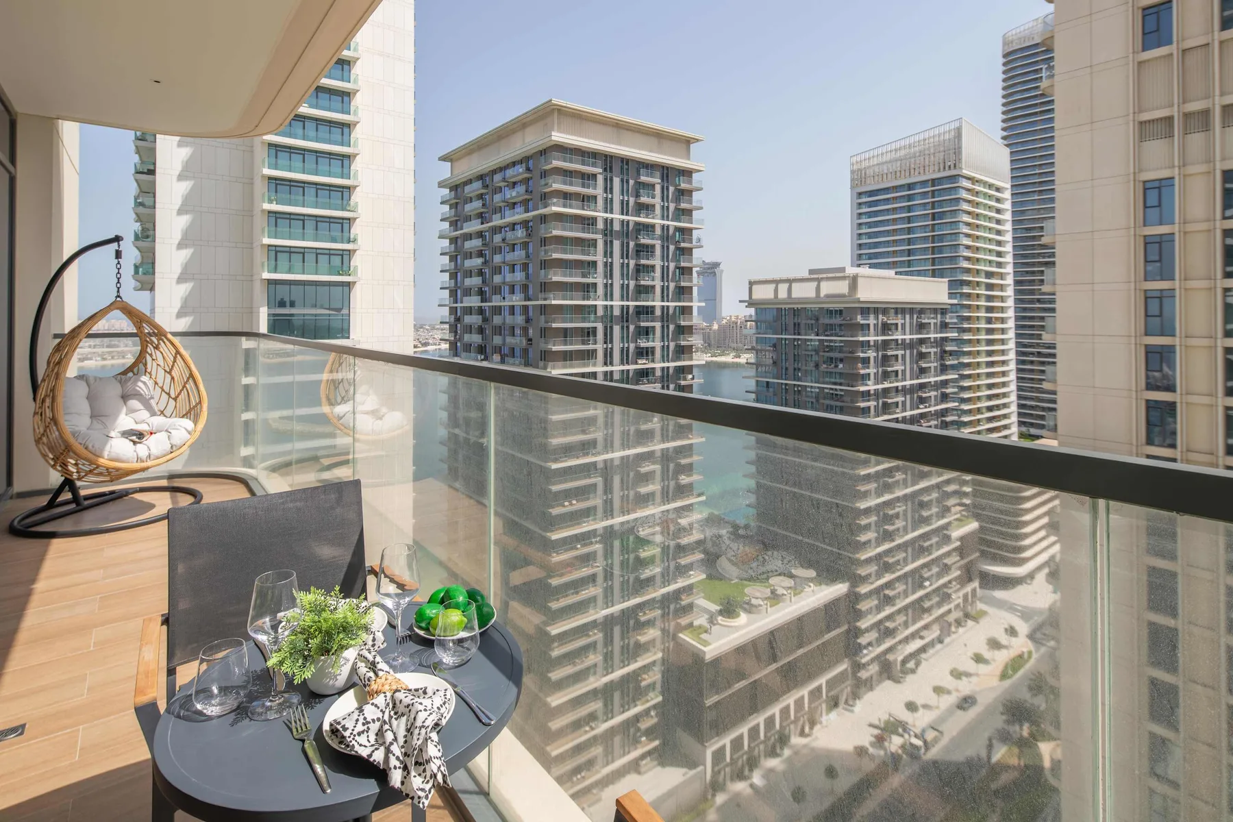 A balcony with glass railings, outdoor seating, and views of nearby high-rise buildings.