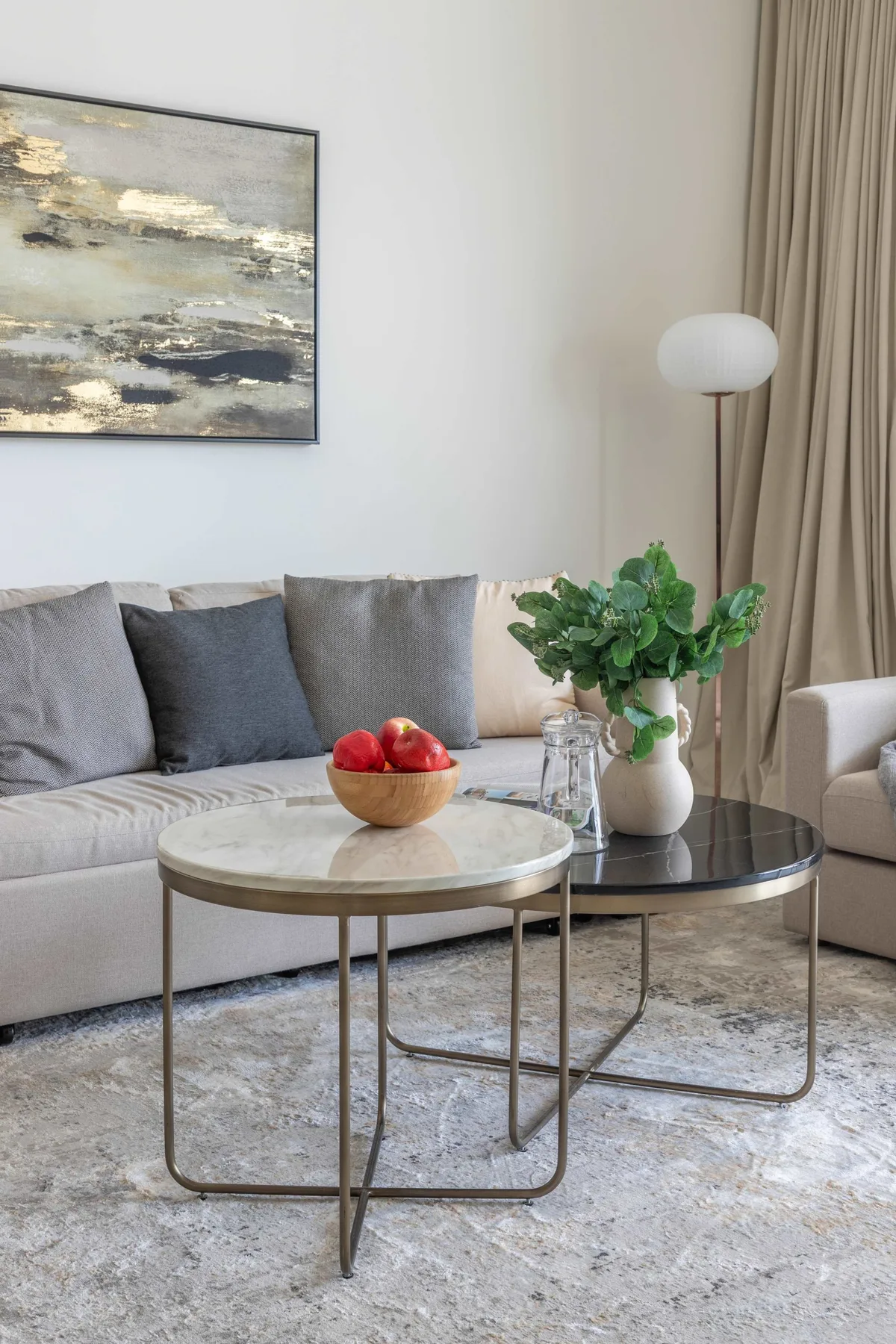 A living room with a sofa, nesting coffee tables, and a leafy plant.