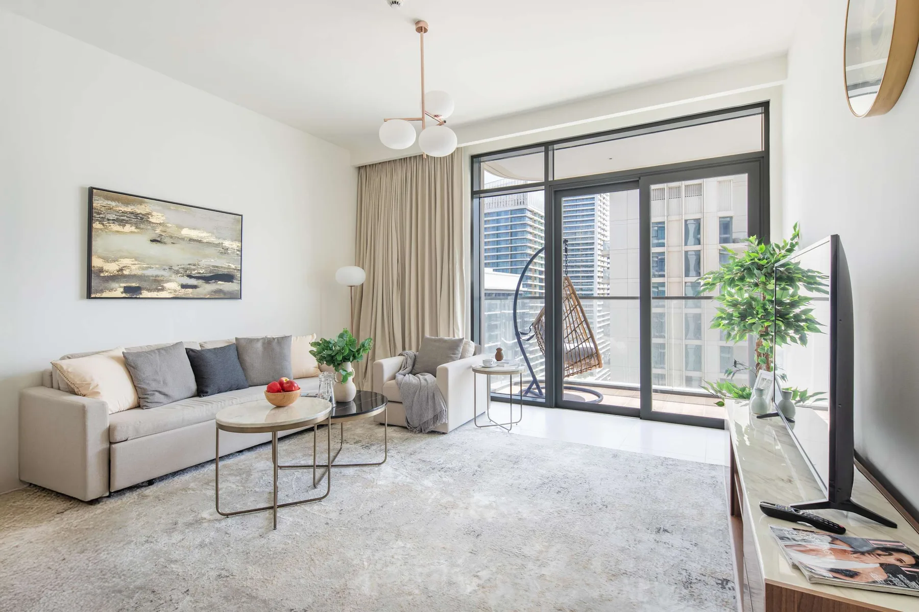 A bright living room with seating and large windows overlooking nearby buildings.