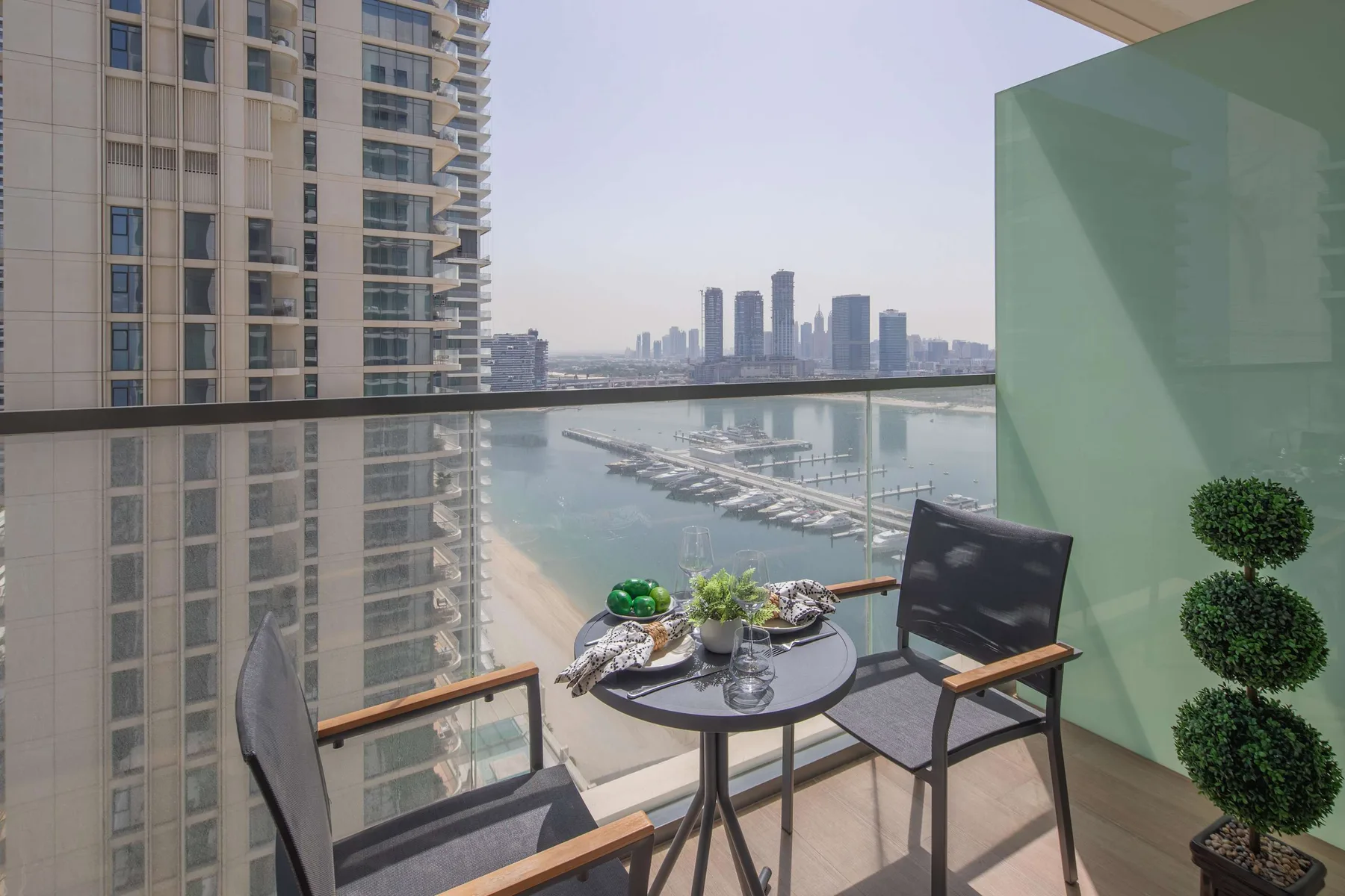 A balcony dining area overlooks the water and a marina.