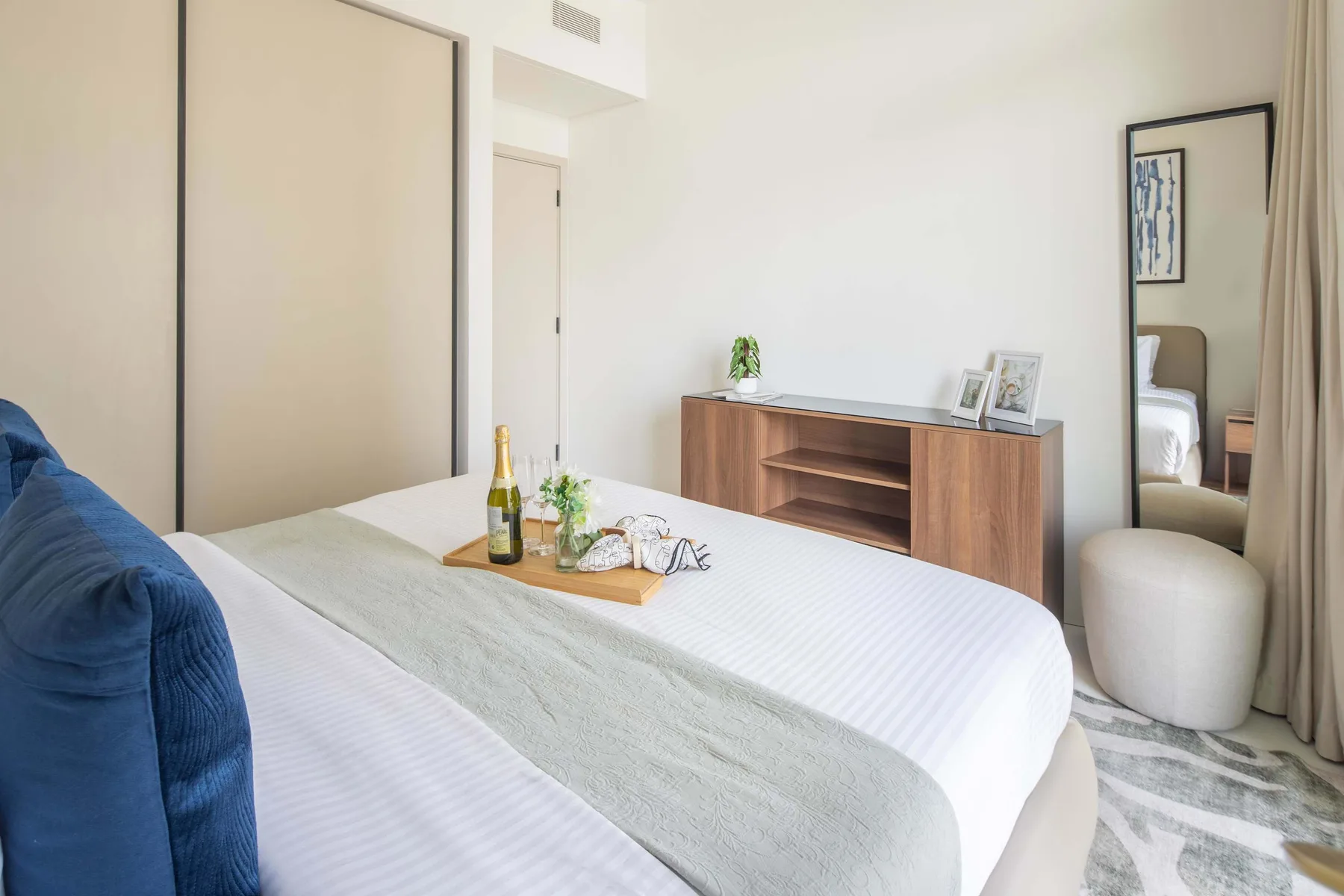 A bedroom with a neatly made bed and a wooden cabinet against the wall.