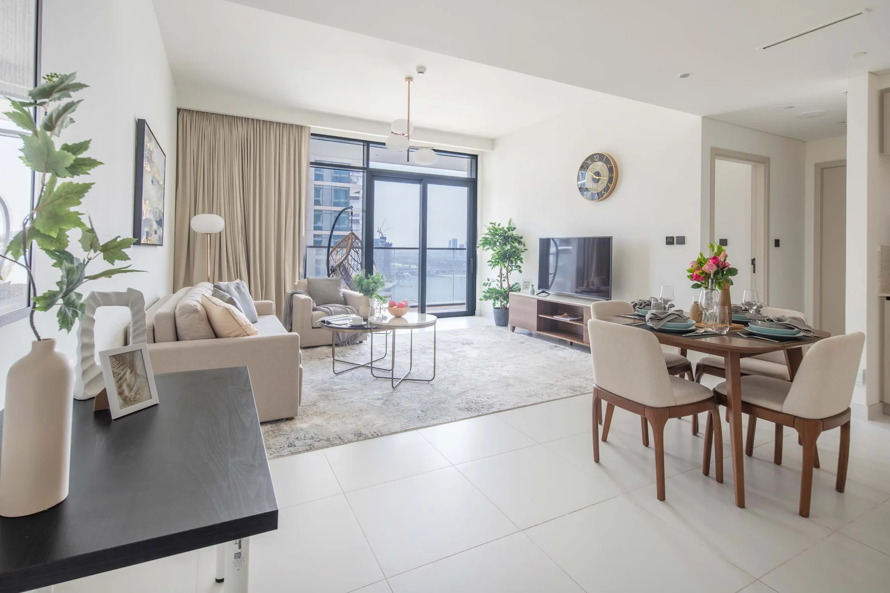 A bright living and dining area with seating, a television, and large windows.