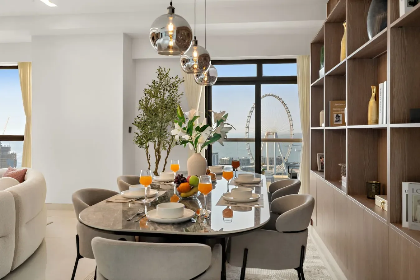 A dining area with a set table beside large windows and built-in shelving.