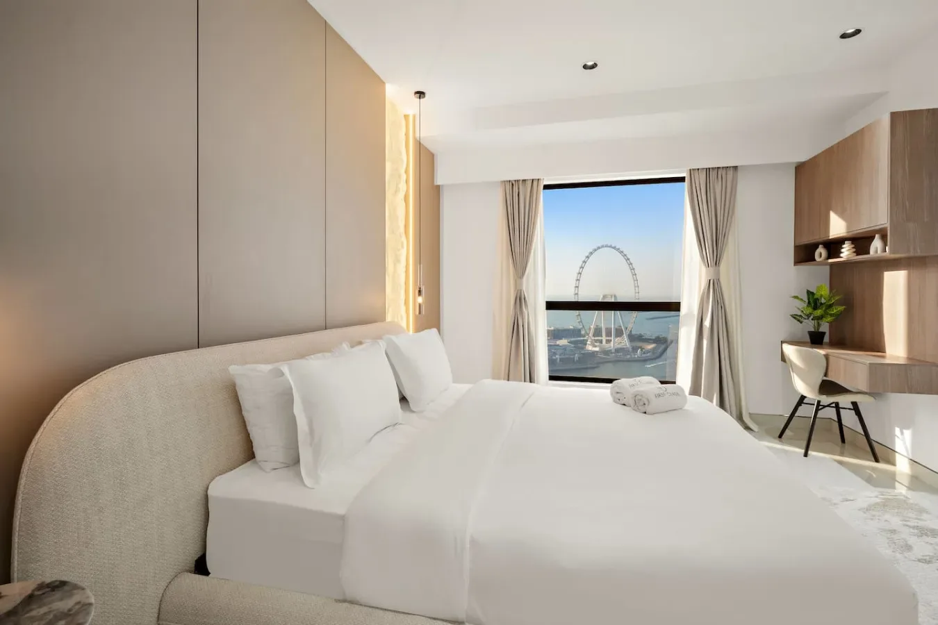 A bright bedroom with a large bed and a window overlooking the water.