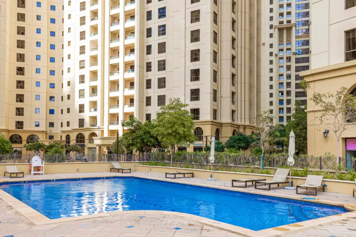 Una piscina al aire libre está rodeada de edificios residenciales altos y jardines.