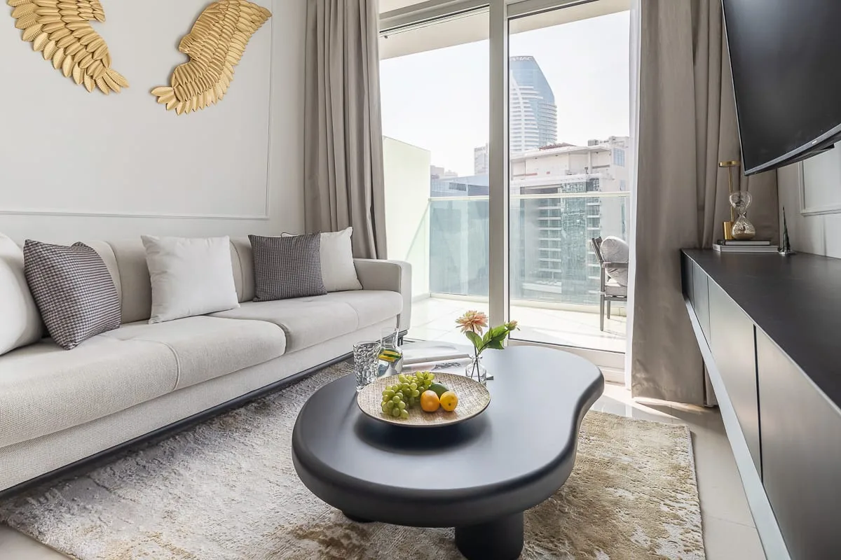 Una sala de estar con sofá, mesa de centro y puertas corredizas de vidrio que dan a un balcón.