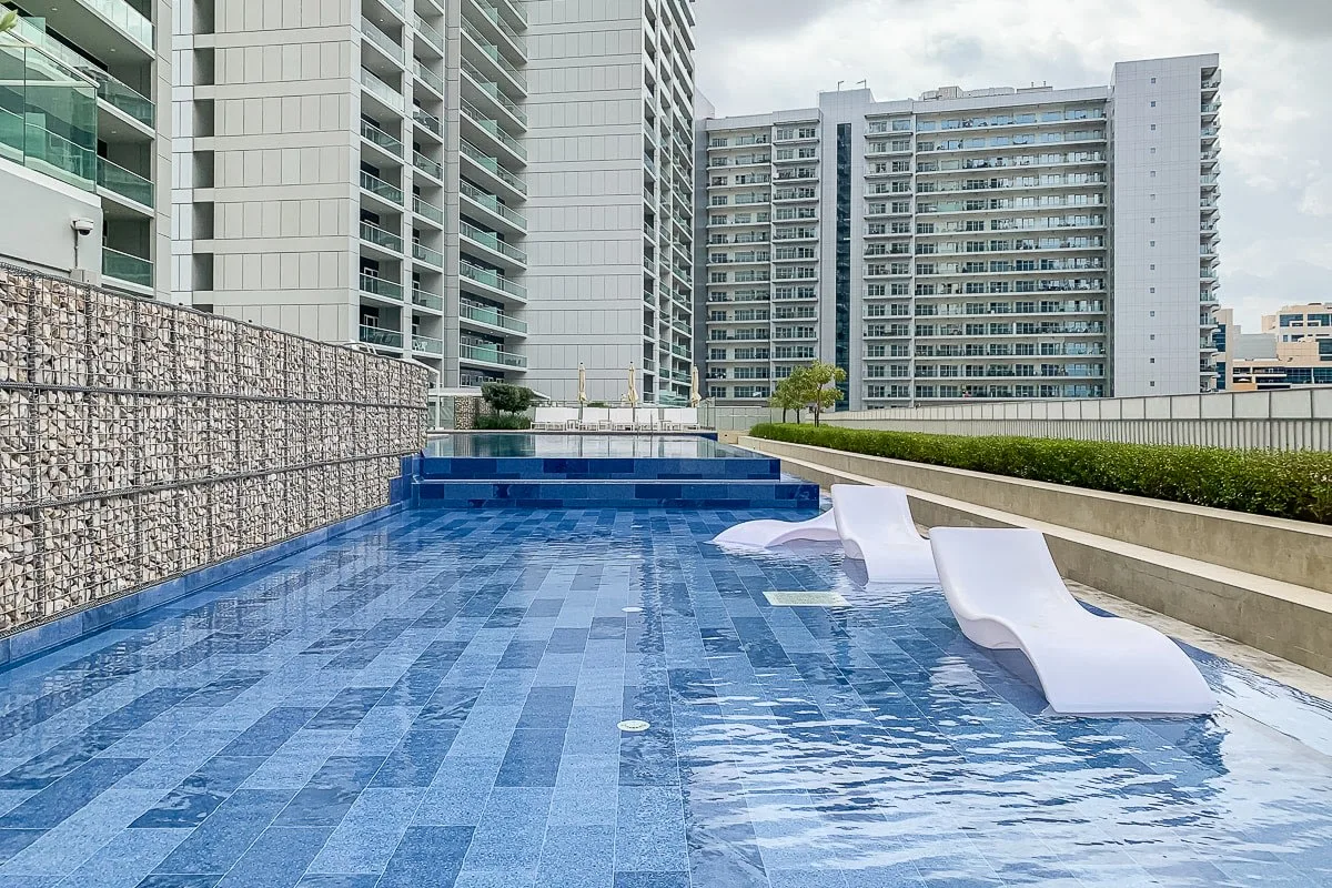 A rooftop swimming pool with blue tile and submerged loungers.