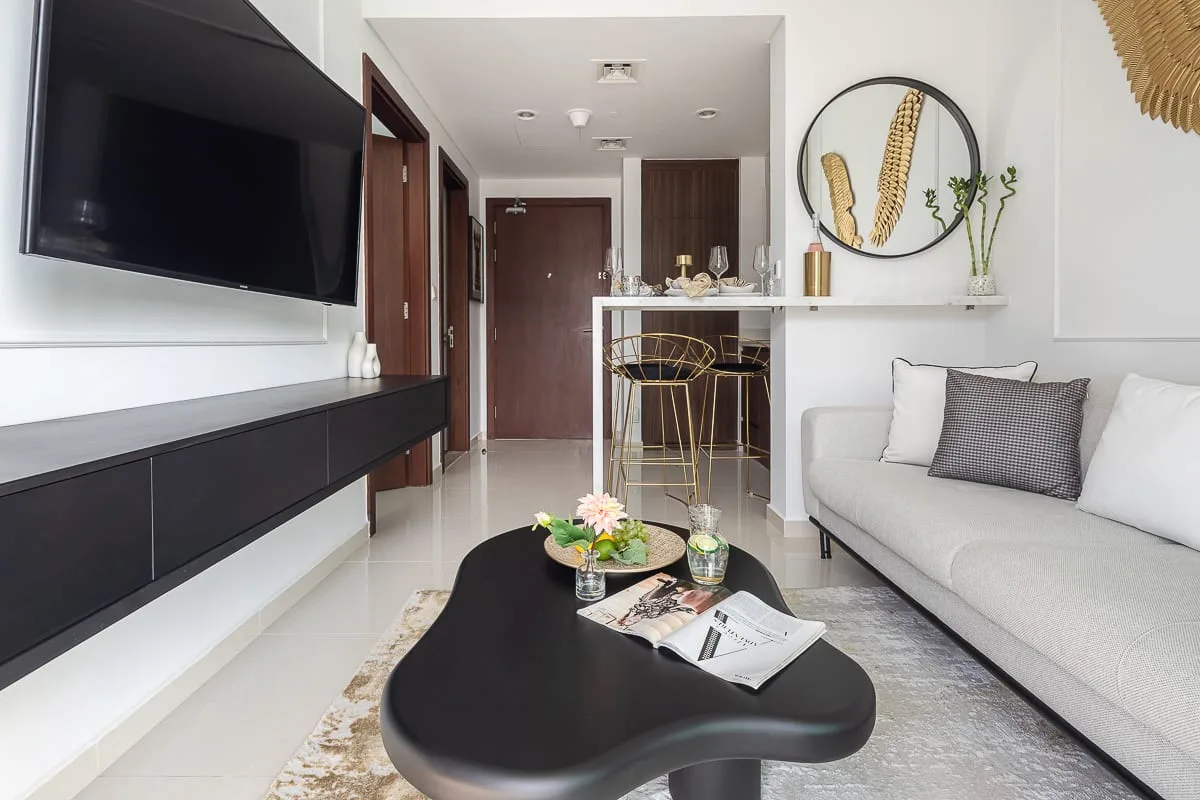 Una sala luminosa con televisor, asientos y una mesa de centro.
