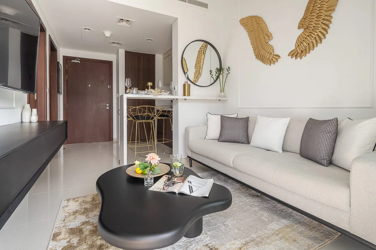 Una sala luminosa con un sofá blanco y una mesa de centro negra.
