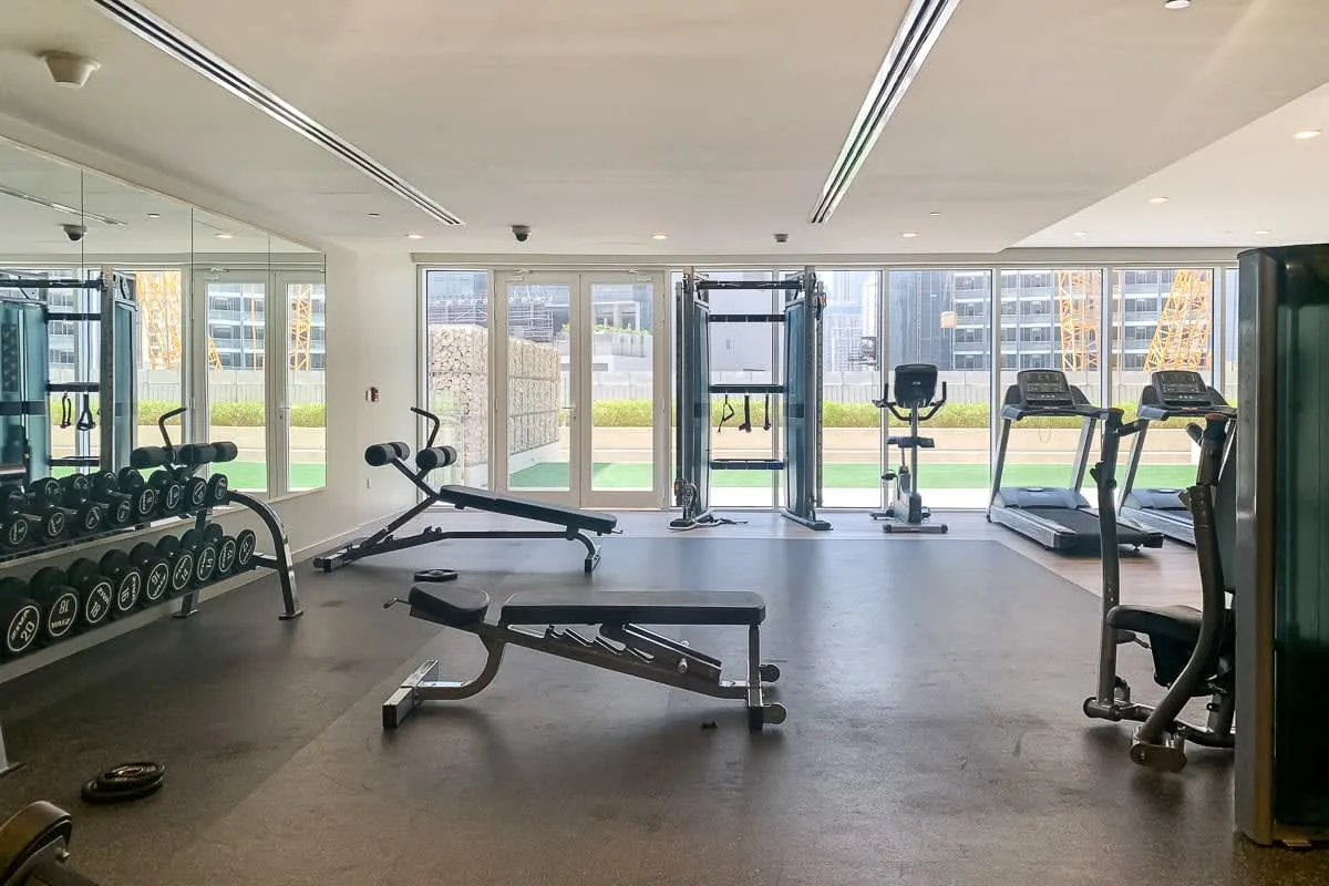 A gym with weight racks, exercise machines, and large windows.