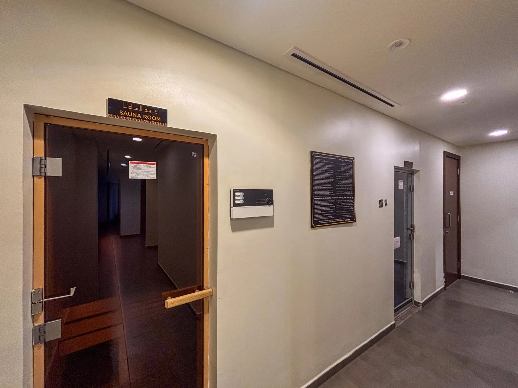 A hallway with a dark glass door and wall-mounted signs.