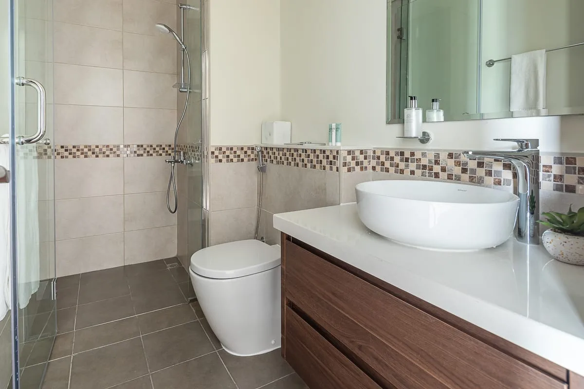 A modern bathroom with a glass shower, toilet, and sink vanity.