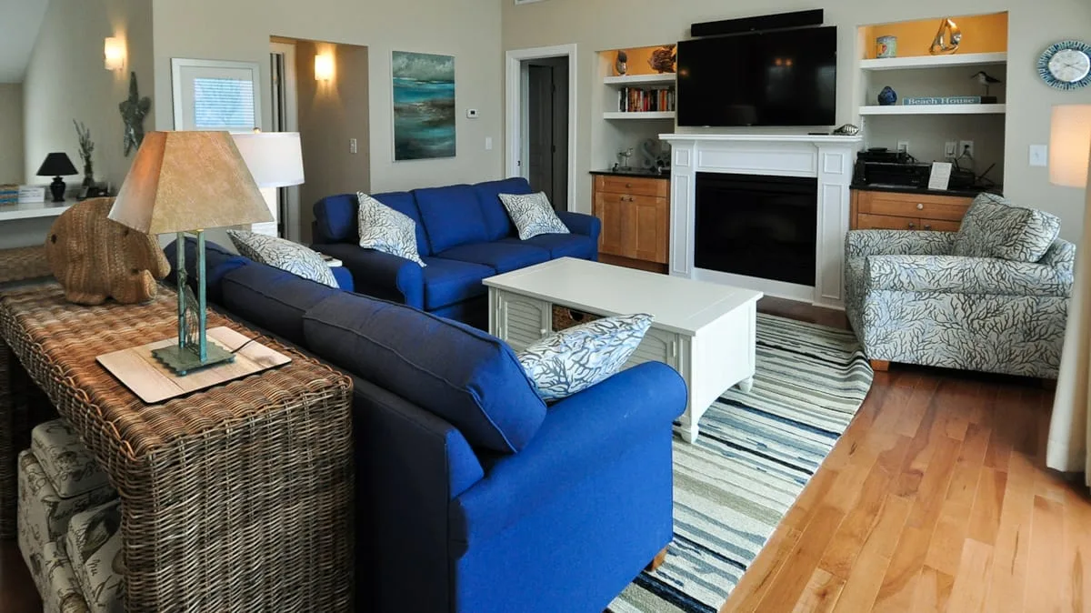 A living room with blue seating, a fireplace, and a television.