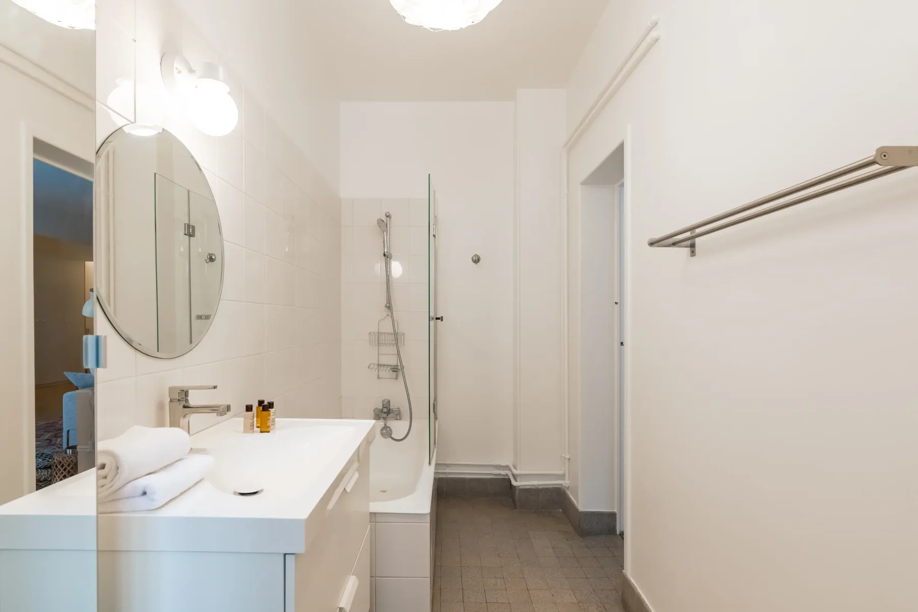 A bright bathroom with a vanity, mirror, and shower.
