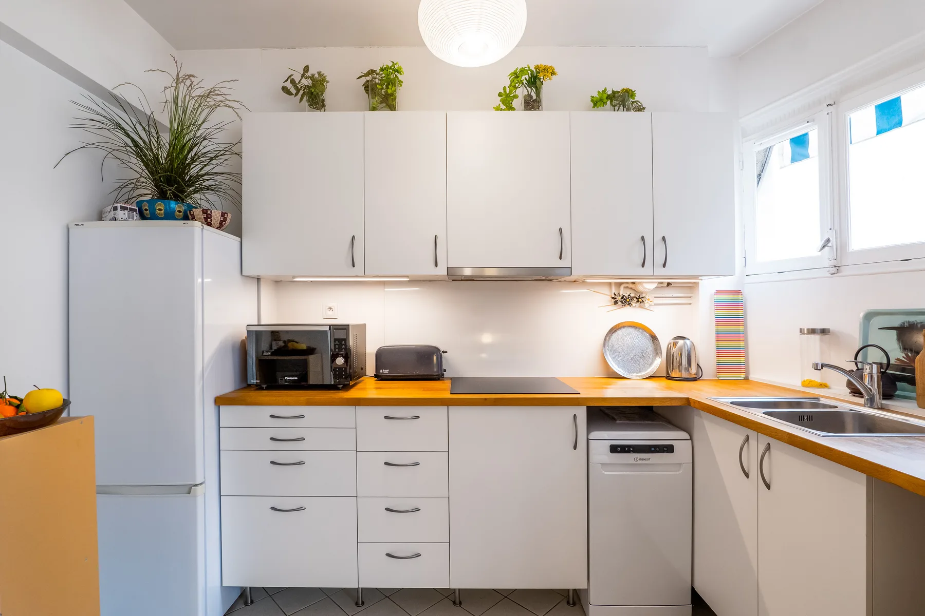 A bright kitchen with white cabinets, wooden countertops, and a window.