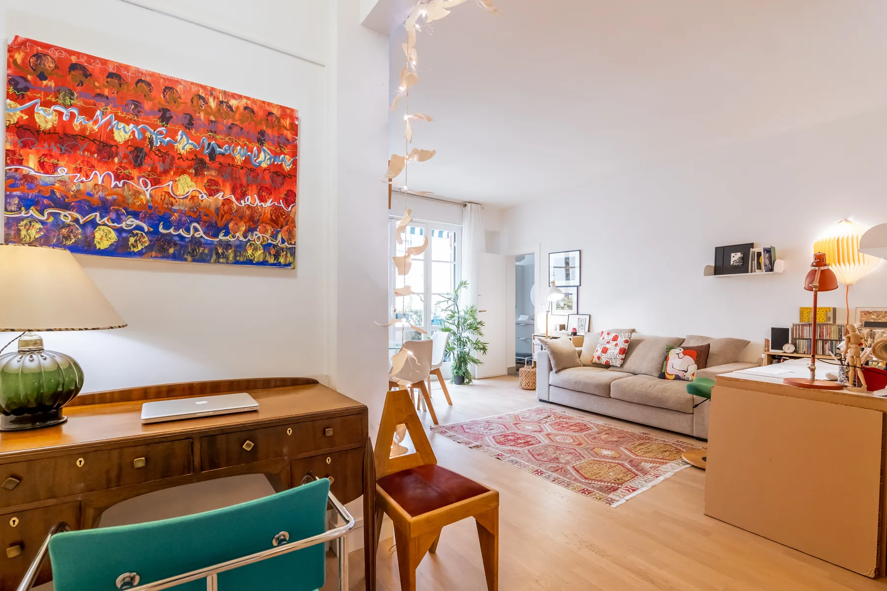 A bright living room with a beige seating area and colorful wall art.
