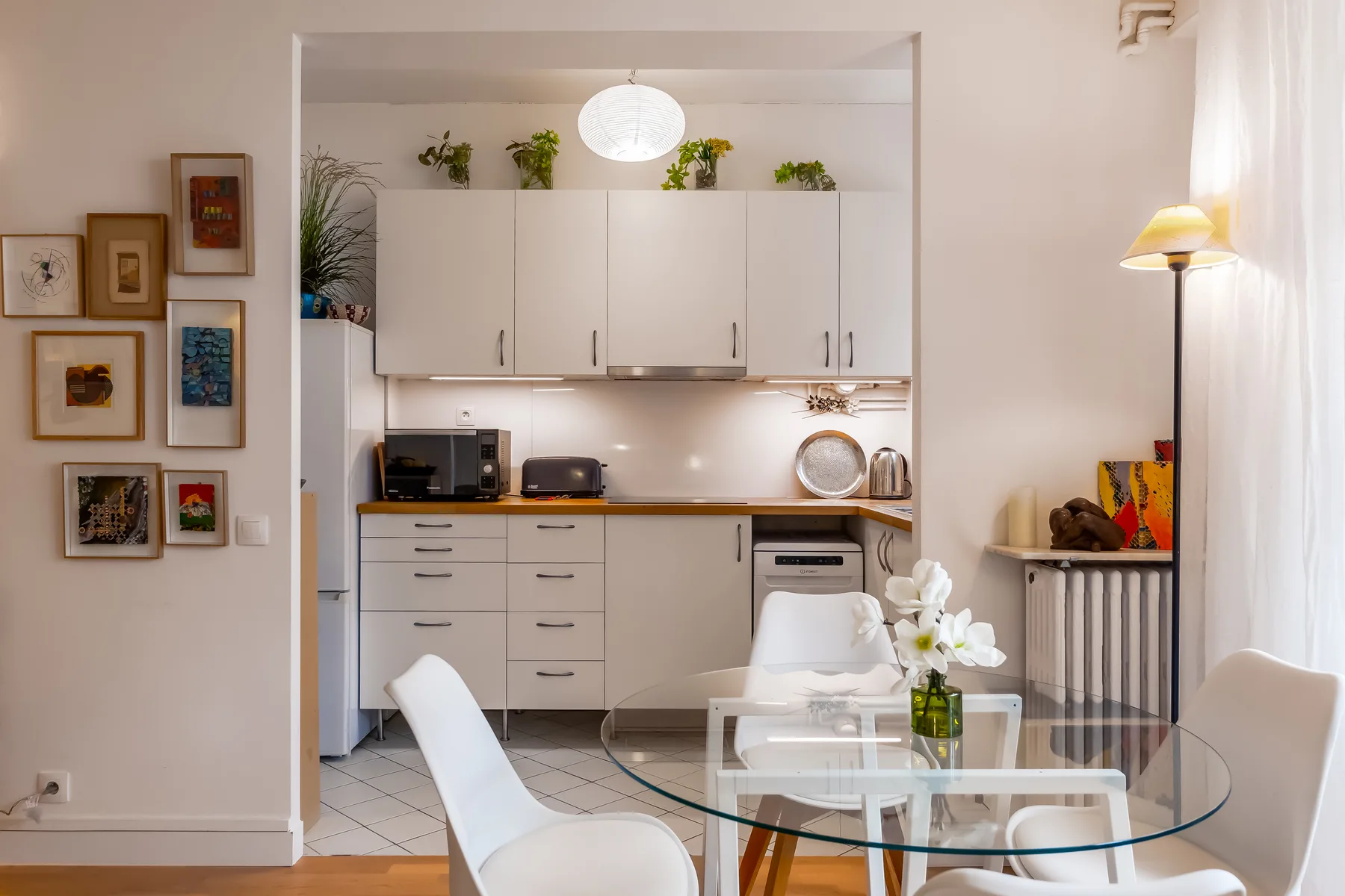 A bright kitchen and dining area with white cabinetry and a glass dining table.