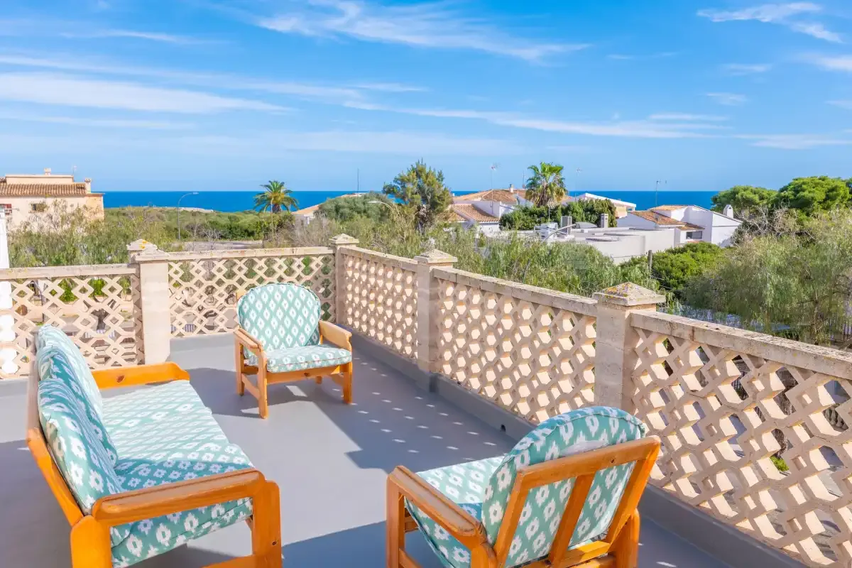 Una terraza con asientos acolchados ofrece vistas a tejados cercanos y al mar.